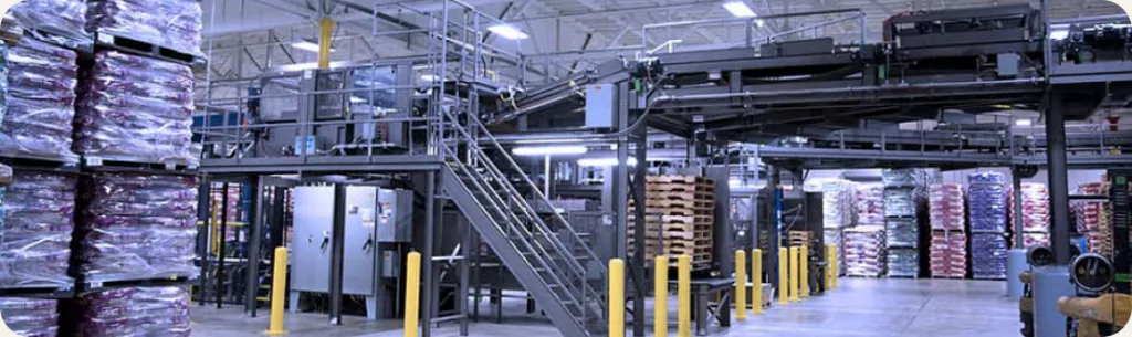 Inside a pet food production facility, with machinery and pallets of bagged food